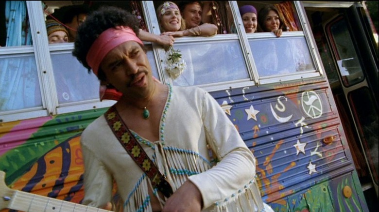 Jimi Hendrix (Che Timmins) stands in front of a bus full of hippies in Nightmares & Dreamscapes: From the Stories of Stephen King