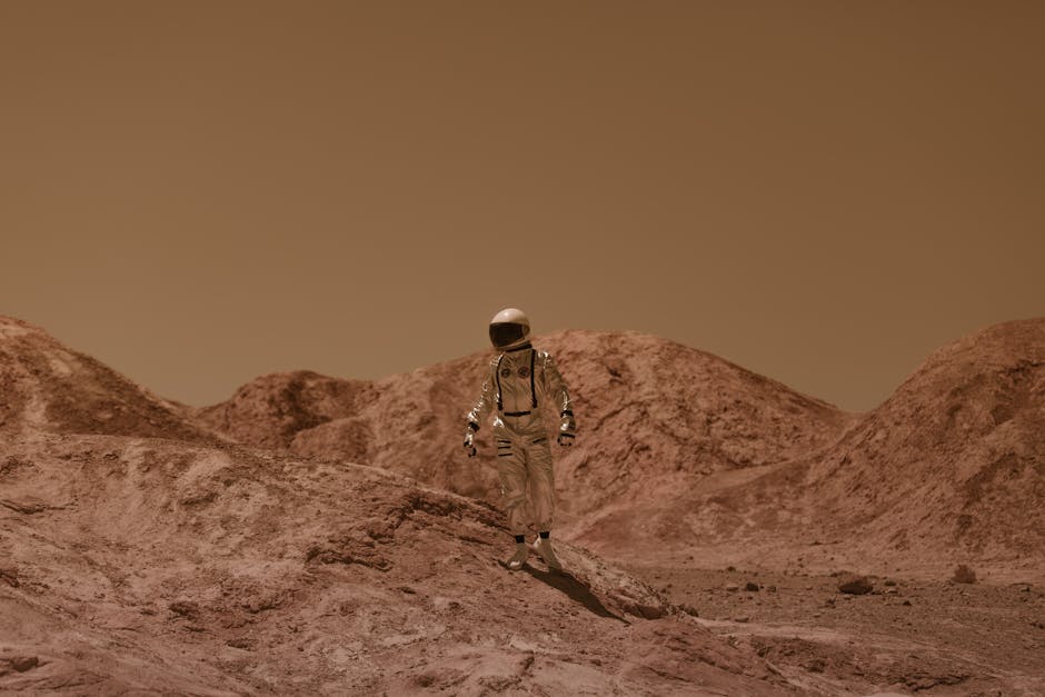 An astronaut in a spacesuit ventures across a barren, Mars-like desert landscape.