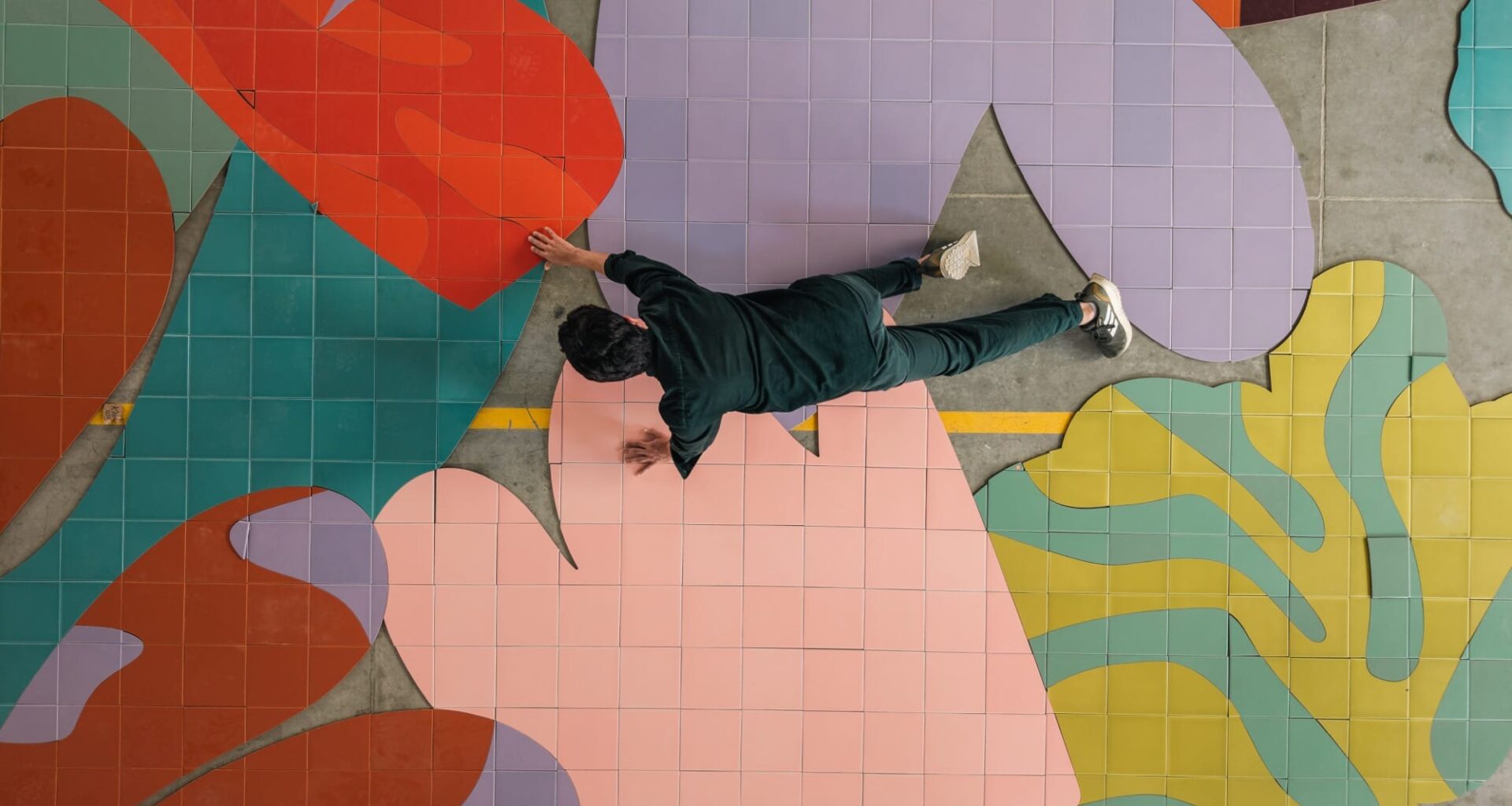 a person crawls atop colorful ceramic tiles on a floor