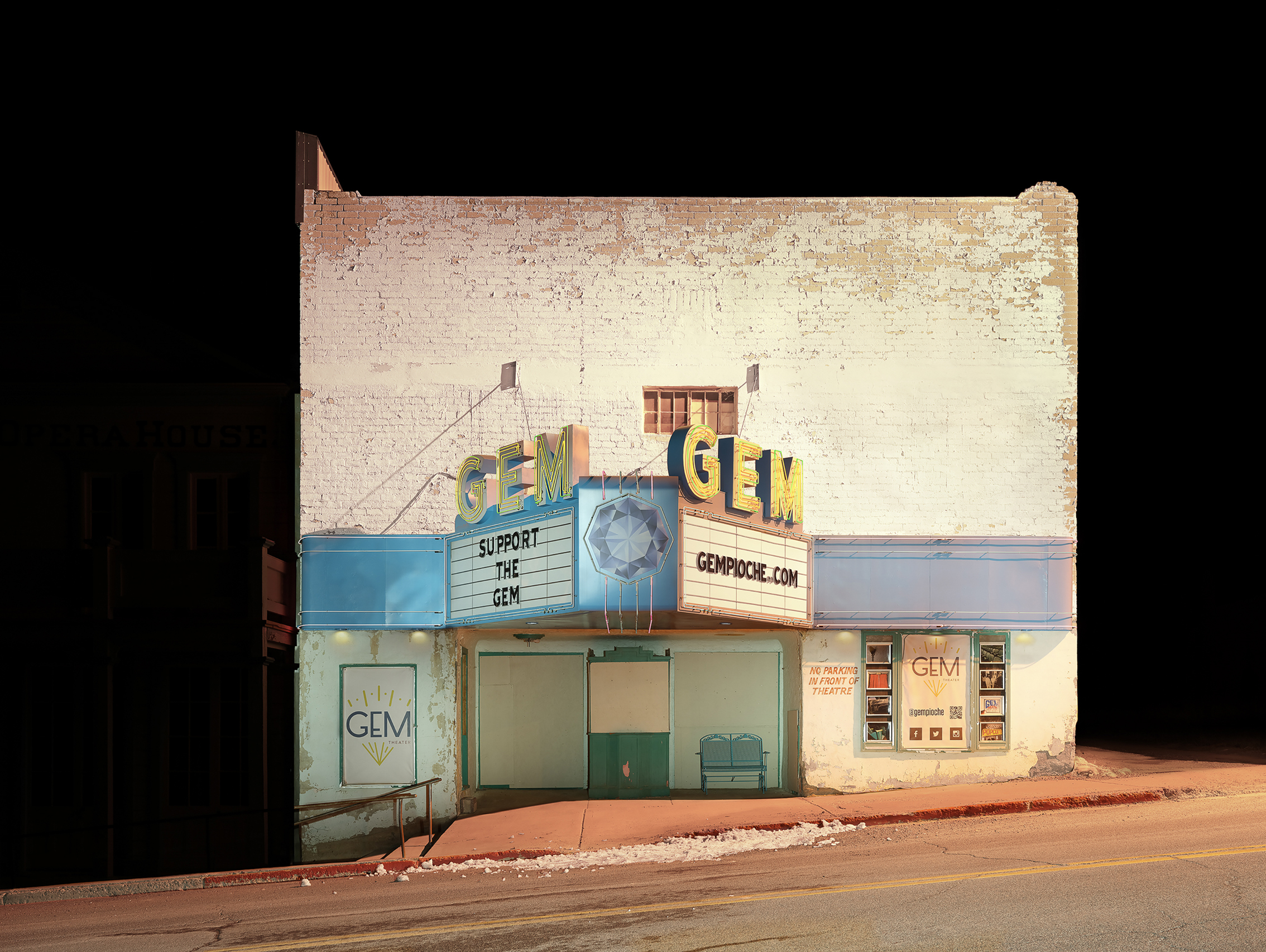 Gem theater with illuminated signs reading "Support the Gem" and "GEMPIOCHE.COM" on a weathered white brick building