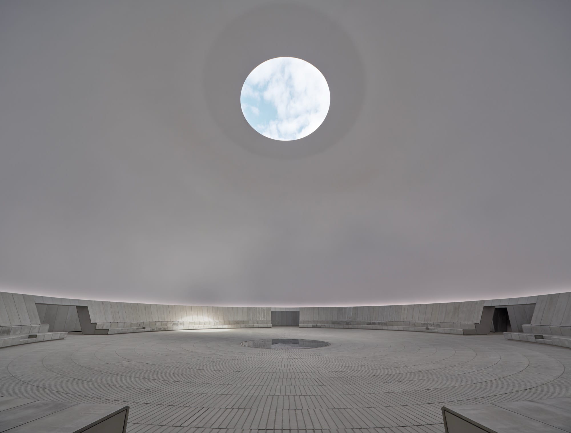 a large-scale light exhibition by James Turrell featuring a sky filled hole in a gray dome