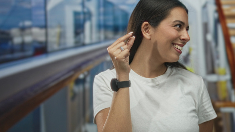 A woman smiling and making a pinching notion with her hand with a smartwatch attached to her wrist