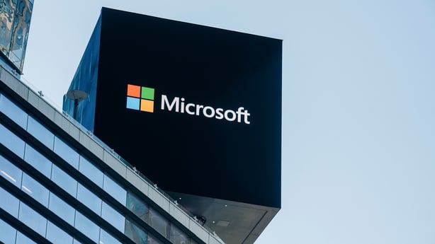 a black square sign with white text and the Microsoft logo on top of a building