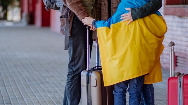 Ukrainian refugee family waiting for train in station, Ukrainian war concept.