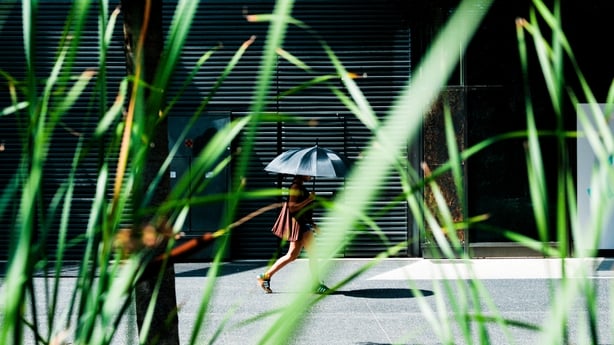A woman walks near a shopping centre in Grenoble sheltering under a parasol to protect herself from the heat during an afternoon of intense heat linked to an unprecedented heatwave on Friday 26 June 2026. (Photo by Benoit Pavan / Hans Lucas via AFP)