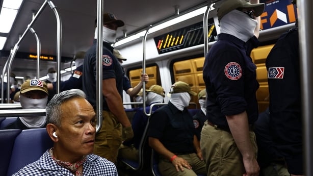 A passenger looks on as members of Patriot Front ride the Washington Metro.