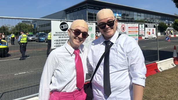 Two young women wearing bald caps, sunglasses and white shirts 