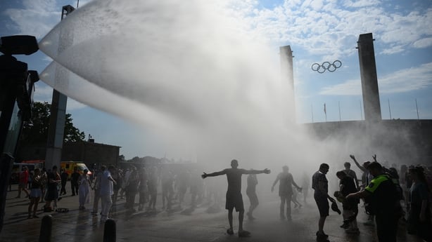 Police use water cannon to spray people with water as the arrive at the Olympic stadium for a concert of US singer Bruno Mars on June 28, 2026, in Berlin