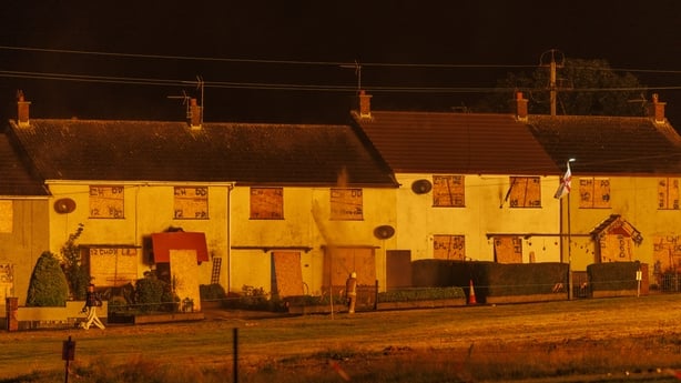A member of the Northern Ireland Fire and Rescue Service hoses down homes opposite a bonfire