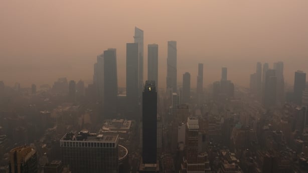 Smoke from wildfires in Canada shrouds the sun as it sets behind Hudson Yards, seen from the 86th-floor observation deck of the Empire State Building