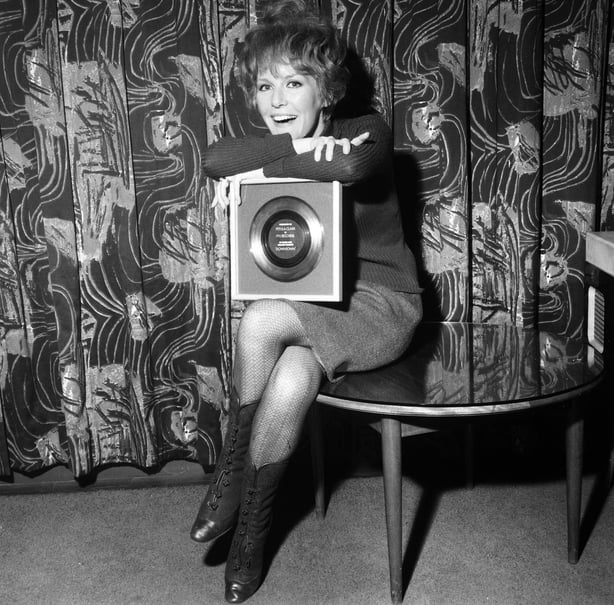 Petula Clark receiving a gold disc for Downtown after it sold a million copies, 1 March 1965. (Photo by Tom King/Mirrorpix/Getty Images)