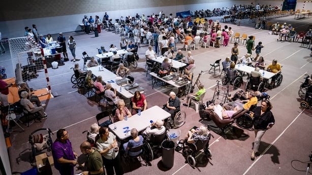 Several people evacuated from the municipality of Aldea del Fresno are seen in a hall with tables