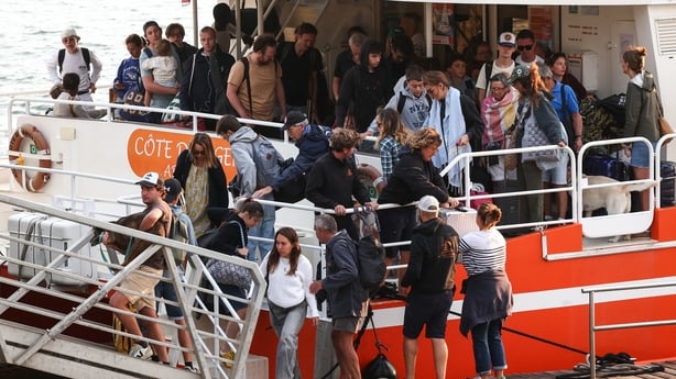 Holidaymakers from Lege-Cap-Ferret disembark from a boat upon their arrival in Arcachon during an evacuation operation of the entire Cap-Ferret peninsula, in southwestern France, on July 24, 2026 whilst a wildfire is spreading across the area. The fire, which is thought to have started accidentally 