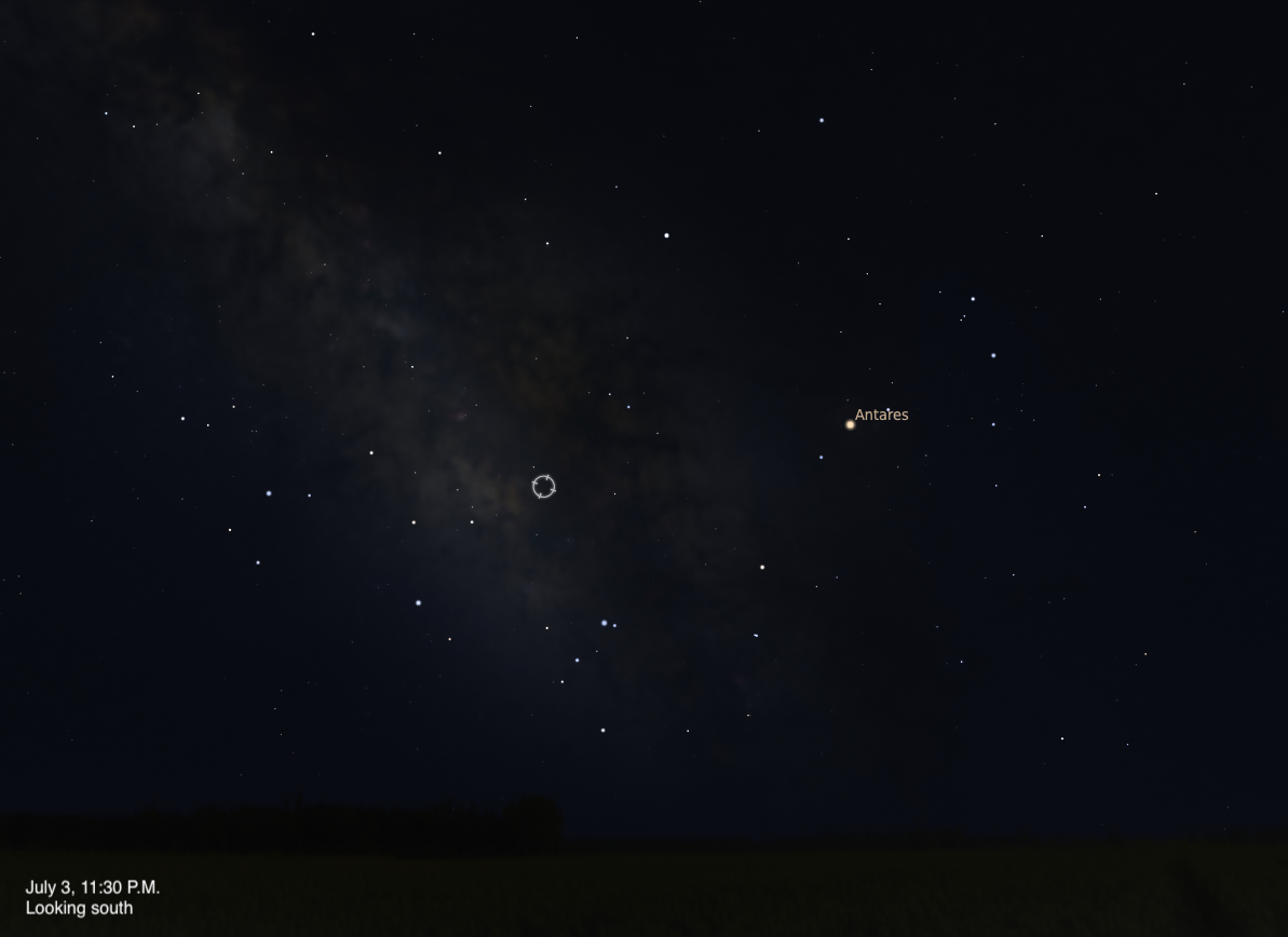 A simulated night sky looking south on July 3, 2026 at 11:30 P.M. A small circular target indicator marks an unnamed object embedded in the faint glow of the Milky Way near the center of the frame. The bright orange-red star Antares is visible to the right, and the dense star clouds of the Milky Way stretch across the left side of the image.