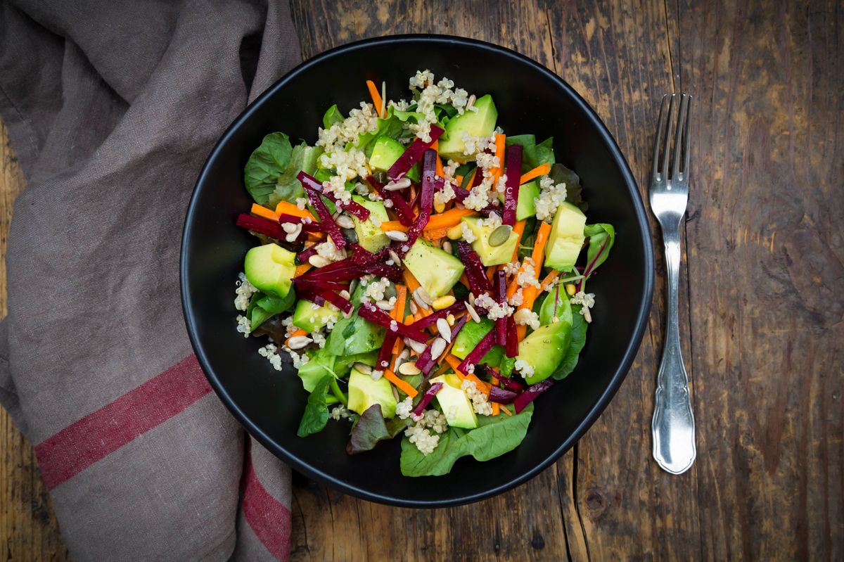 Bowl of autumnal salad with lettuce, carrots, avocado, beetroot, pumpkin and sunflower seeds, pomegranate and quinoa
