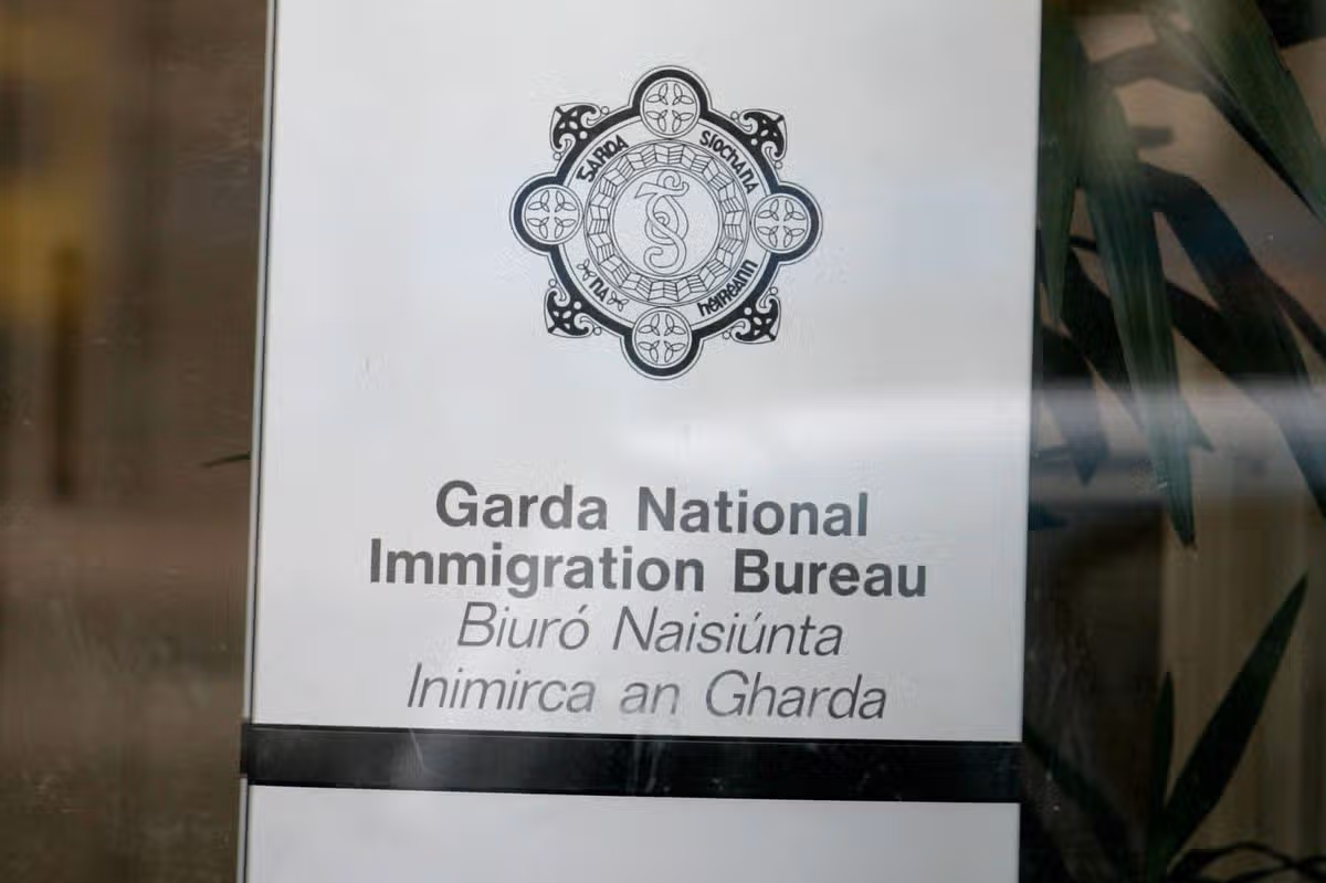 An official sign for the Garda National Immigration Bureau, displayed on a transparent surface, features a logo and the organization's name in bold text.