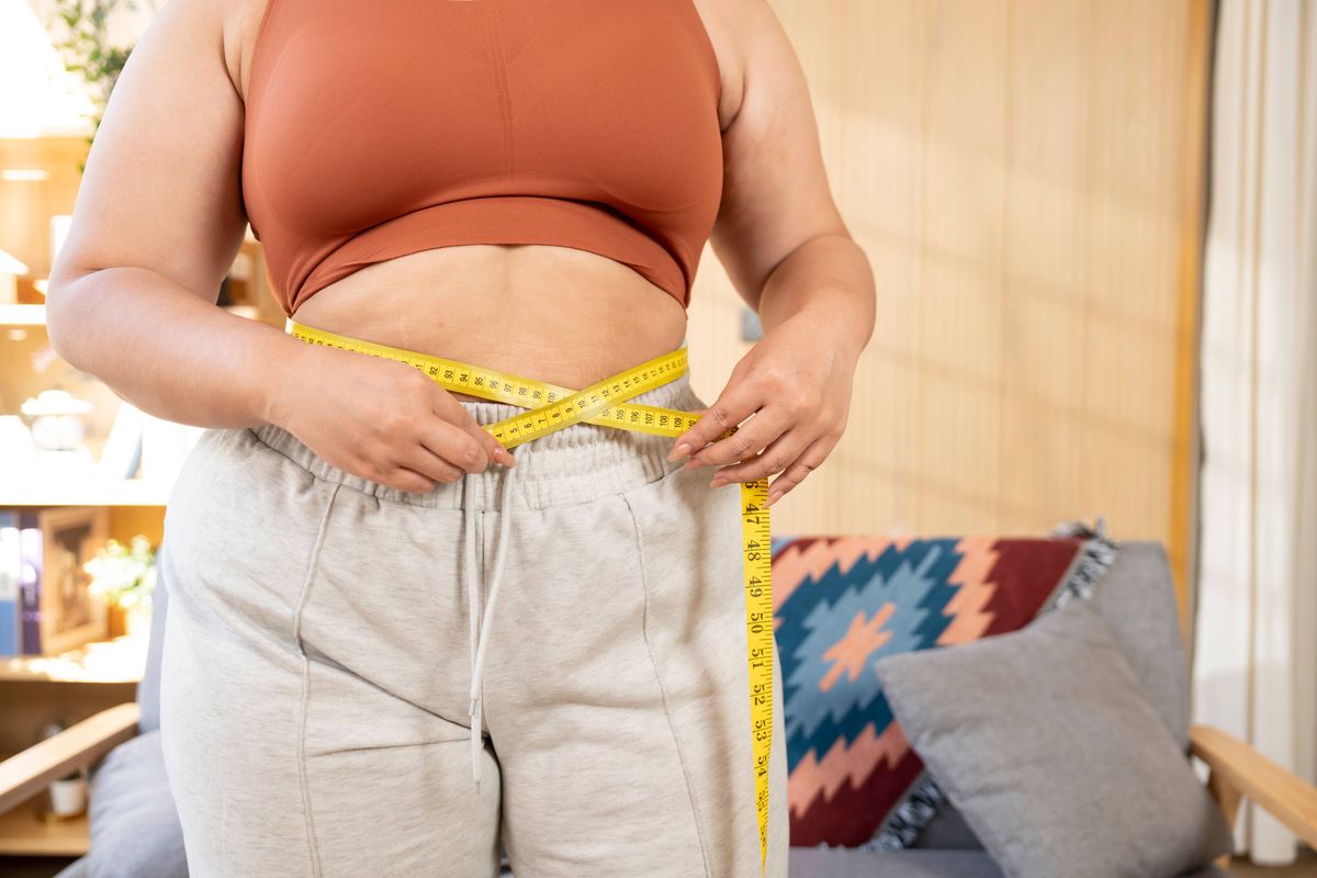 Woman using tape measure on waist