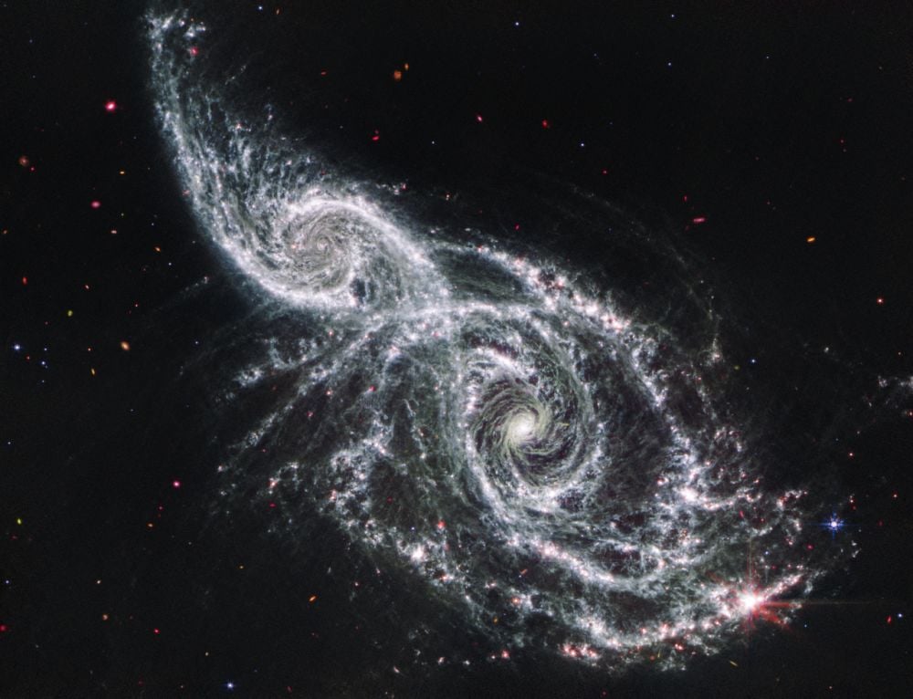 This JWST MIRI image shows two galaxies in the early stage of merging. The larger spiral, NGC 2207, is tidally stripping the gas from the smaller galaxy, IC 2163. Eventually, in about a billion years, they will merge. Image Credit: NASA, ESA, CSA, STScI - Galaxies IC 2163 and NGC 2207 (Webb MIRI Image), Public Domain, https://commons.wikimedia.org/w/index.php?curid=154773560