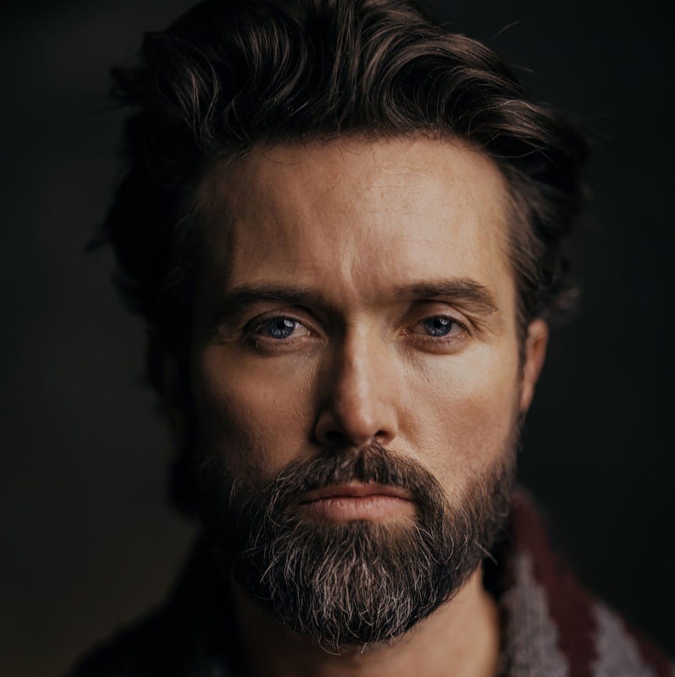 man with a beard and sweater looking directly at the camera, dark background man with a beard and sweater looking directly at the camera, dark background