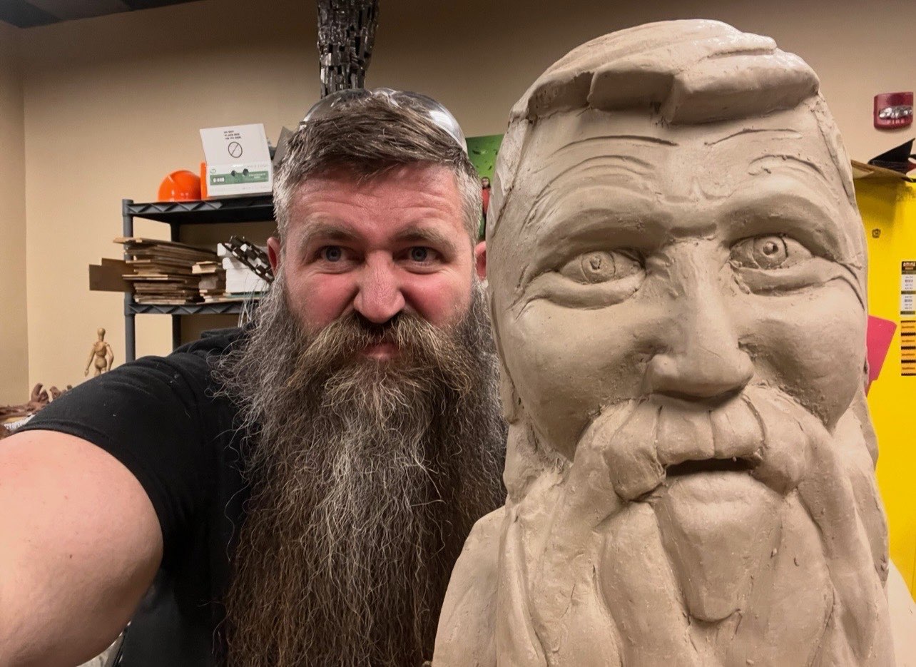 Charles Dan Schluckebier posing next to a sculpture of himself that he sculpted. Courtesy Photo
