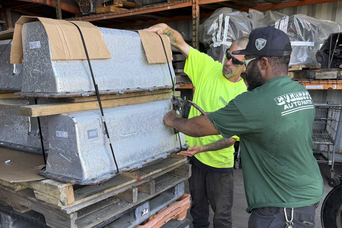Chris McQuiggen and Archie Brewton of Everett Auto Parts strap two Chevy Volt batteries to a pallet in preparation for shipping. The batteries are separated by a layer of wood so they don't make contact with each other. Everett Auto Parts found a battery recycler who will accept these hybrid vehicle batteries, but the salvage yard won't make any money off of them.