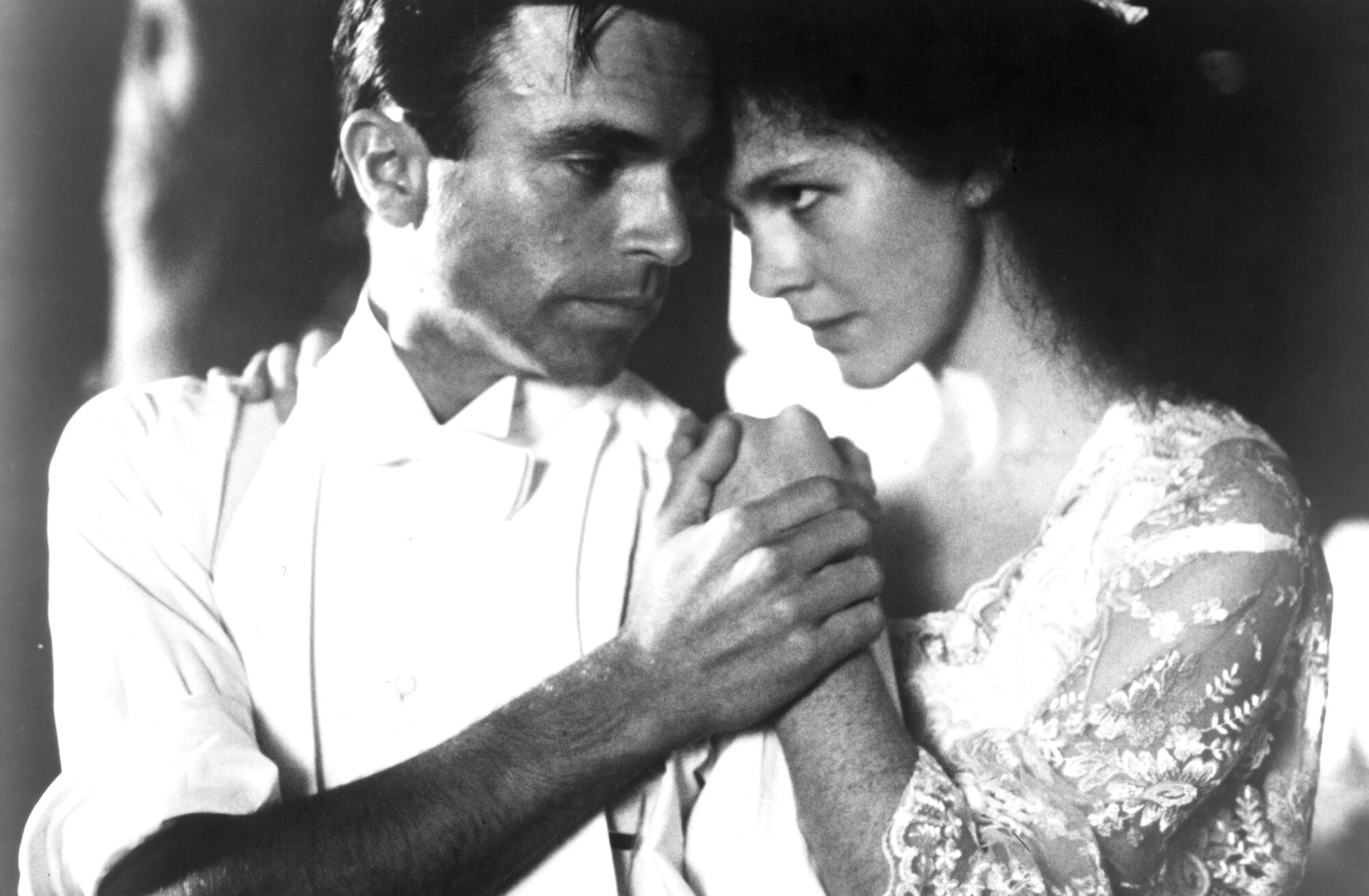 A man tenderly holds a woman's hand.