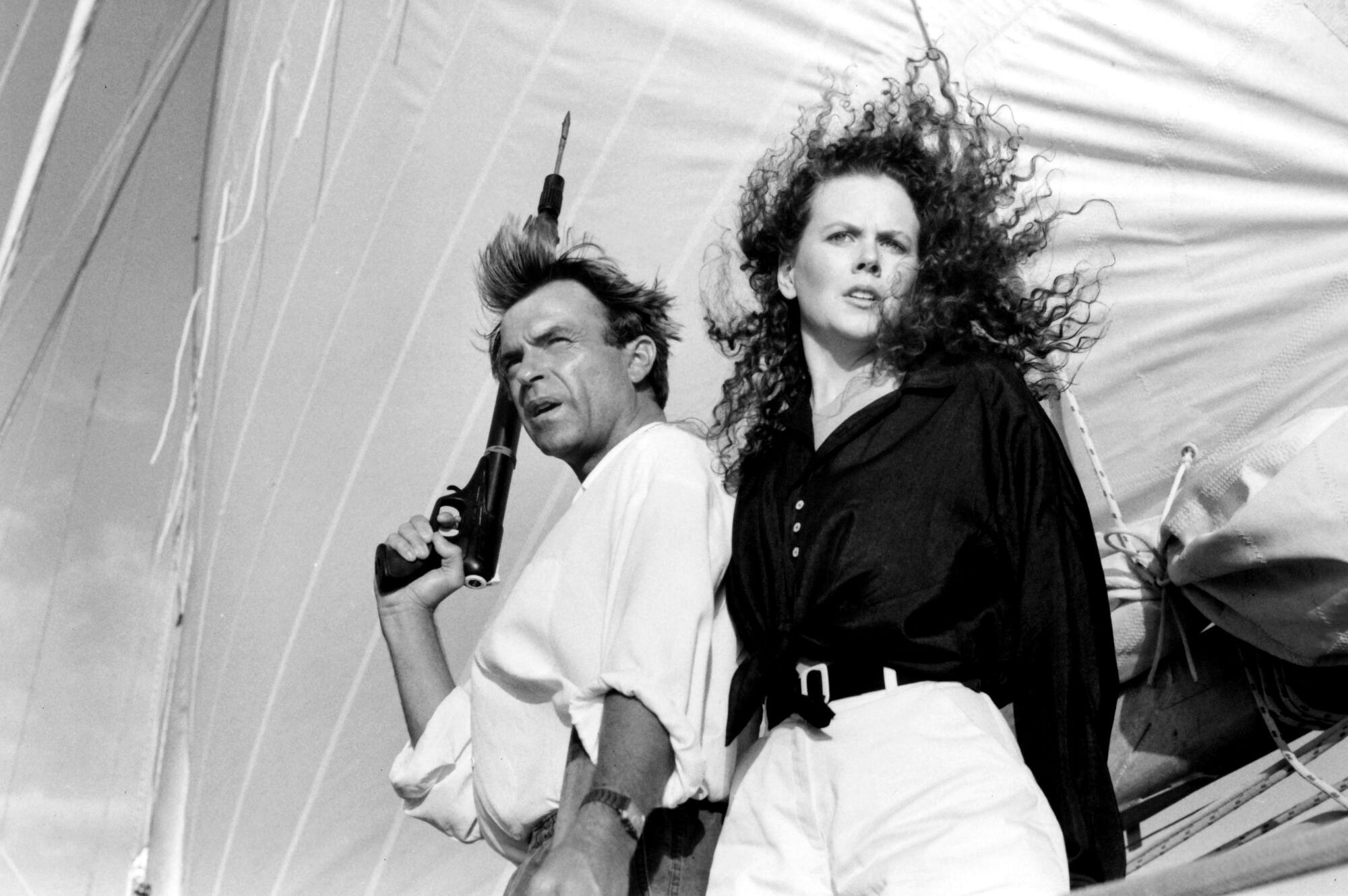 A man with a flare gun stands with a woman on a boat.