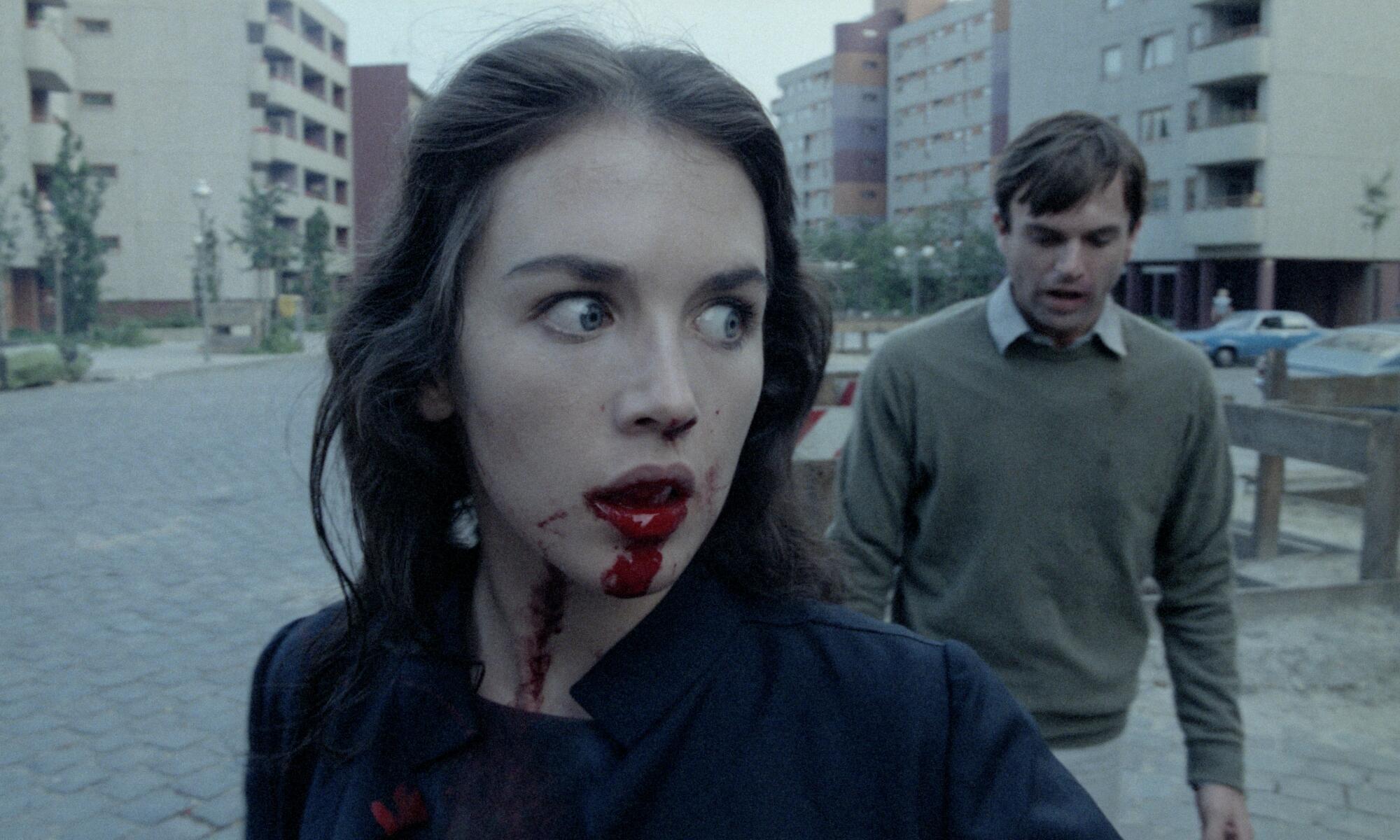 A woman with a bloody mouth is pursued by her husband.