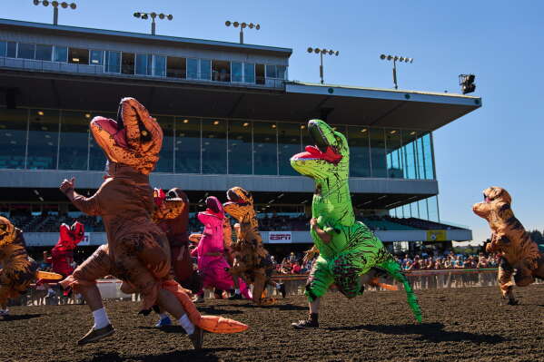 Participants sprint to the finish line during the teen race during the T-Rex World Championship Races at Emerald Downs, Sunday, July 12, 2026, in Auburn, Wash. (AP Photo/Lindsey Wasson)