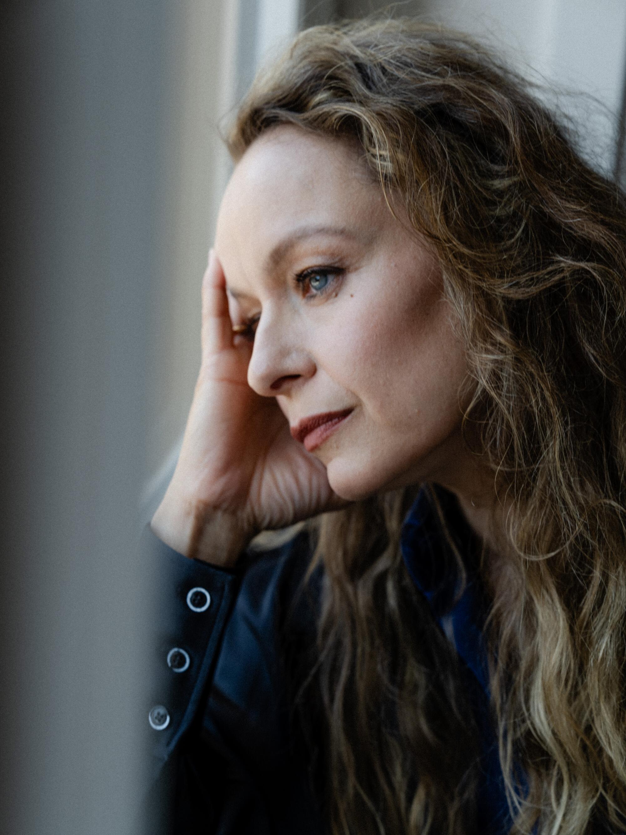 A woman looks out a city window on a gloomy day.