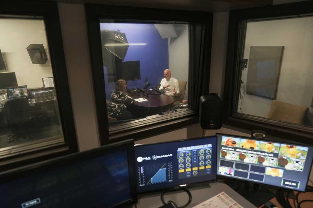 Sarah Downs (left), director of production and video programming at WNIN, talks with Zac Heronemus, CEO of Tri State Food Bank, about an upcoming appearance on the station's Newsmakers series.
