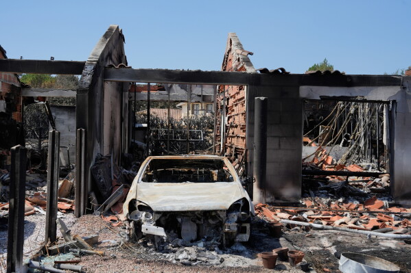 A burned out automobile and the remains of a house after wildfires raged in the village of Le Porge, on the Bay of Biscay, France, Monday, July 27, 2026. (AP Photo/Baz Ratner)