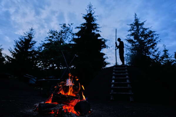 Immo Feldmer monitors the smoldering process as he works at his family-run, traditional charcoal production site near Hasselfelde in Germany's Harz forest, Monday, July 6, 2026. (AP Photo/Matthias Schrader)
