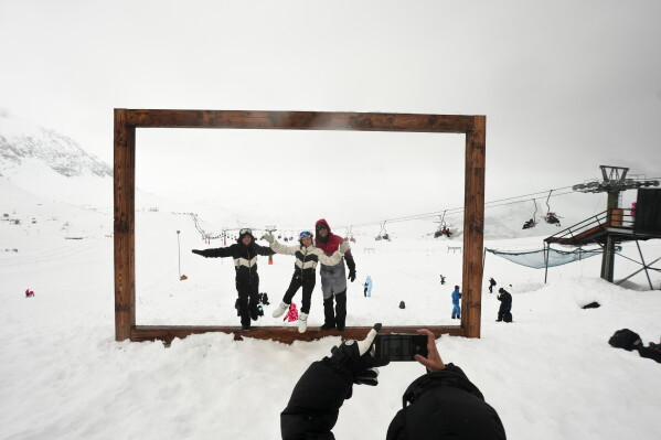 Tourists pose for a photo at the Farellones ski resort on the outskirts of Santiago, Chile, Saturday, July 25, 2026. (AP Photo/Esteban Felix)