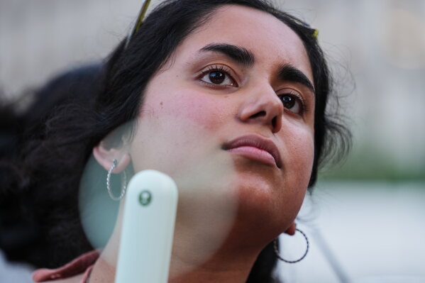 Meghana Jalagam uses a fan to keep cool from the hot weather during a World Cup soccer match between the United States and Bosnia and Herzegovina at a watch party July 1, 2026, in Detroit. (AP Photo/Paul Sancya, File)