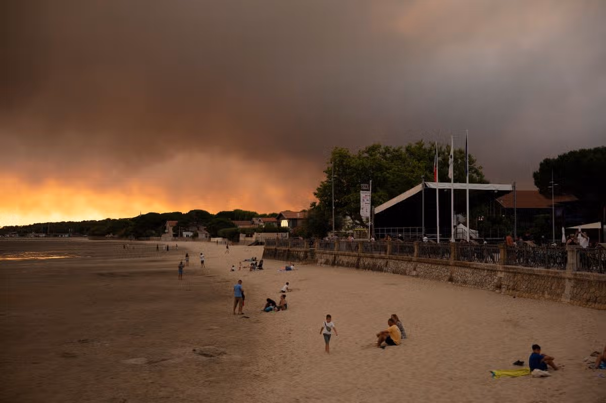 This picture shows people on the beach in Andernos-Les Bains during fire in Lege Cap-Ferret forest, southwestern France on July 23, 2026, as part of the nearby area has been evacuated. A highly virulent wildfire has swept through more than 3700 hectares since July 22 near the Arcachon Basin (Gironde), where nearly 20,000 residents and tourists have been evacuated in total from this area of the Landes de Gascogne forest, already devastated by flames in 2022. (Photo by Olivier MORIN / AFP via Getty Images)