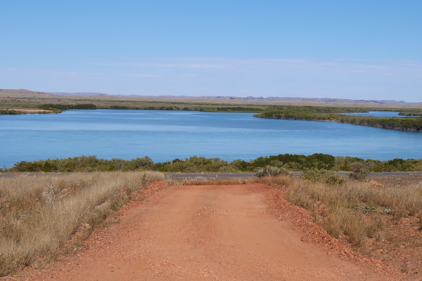 A red dirt road leading to blue water.