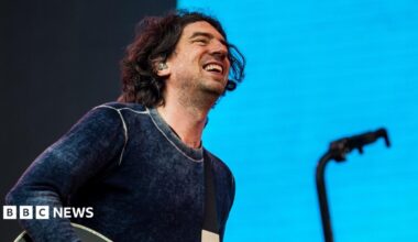 Gary Lightbody of Snow Patrol smiles as he performs on stage at the Latitude Festival in 2025, against a light blue backdrop