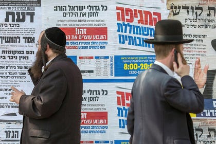 Haredi men stand before posters calling for childhood vaccination against measles during the last outbreak in 2018. Credit: Emil Salman Haredi men stand before posters calling for childhood vaccination against measles during the last outbreak in 2018.