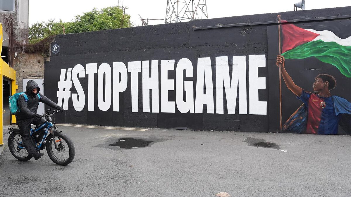 A Deliveroo rider passes the new Lamine Yamal mural outside Bohemians' Dalymount Park, which features the Barcelona star with a Palestinian flag and the words "stop the game", referencing calls to halt the Ireland v Israel European Nations League fixture. Pic: Niall Carson/PA Wire