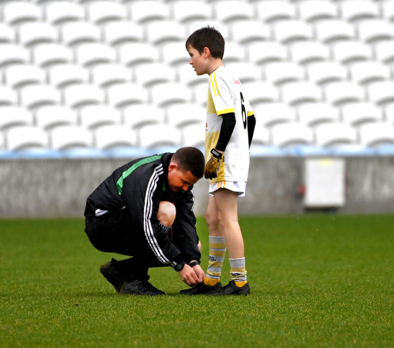 Colm Lyons ties the boot laces of Crossmahon NS's Seán Prendergast during the Allianz Sciath na Scol DF4 final at Páirc Uí Chaoimh in 2023. Picture: Eddie O'Hare