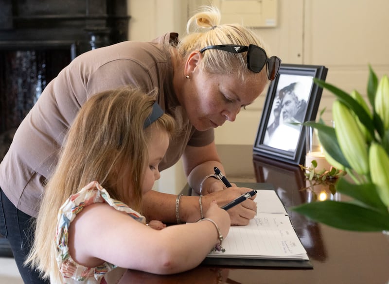 Catherine O’Brien (5) with her mother Charlotte Deane from Mount Street signing the book of condolences in memory of Glen Hansard. Photograph: Collins 