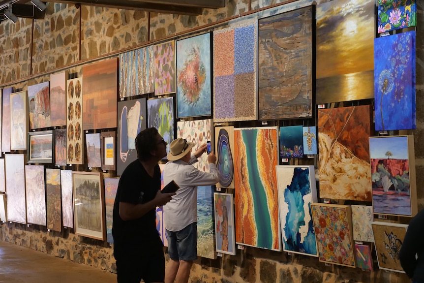 People look at various art on walls.