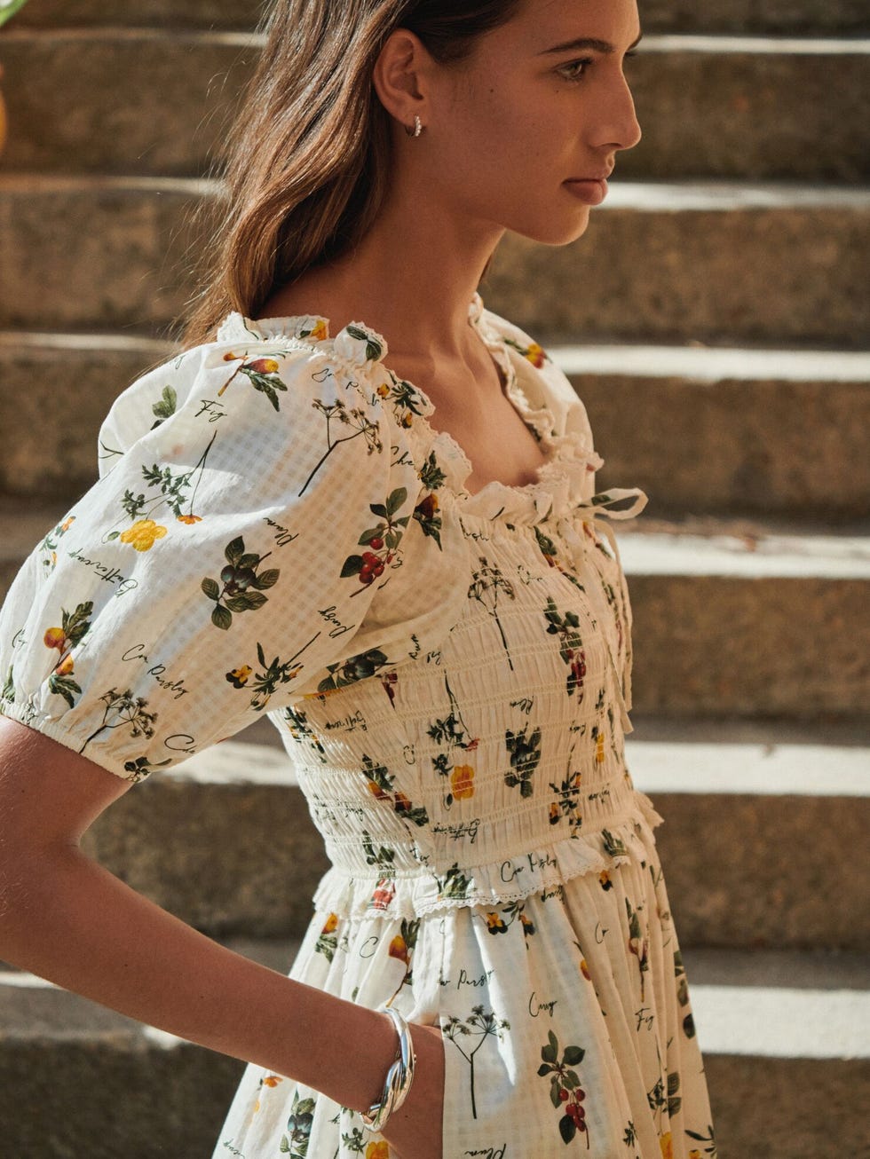 woman in floral dress on stone steps in sunlight. woman in floral dress on stone steps in sunlight.