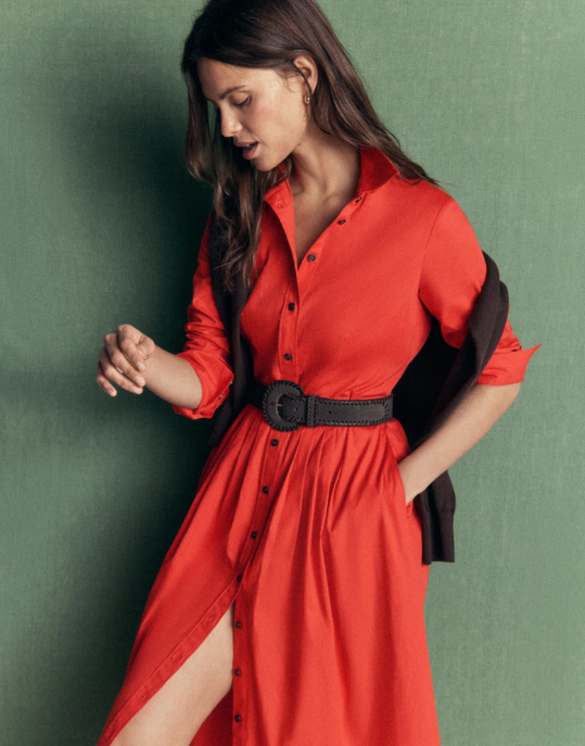 Woman in a long red dress with black belt against green background woman in a long red dress with black belt against green background
