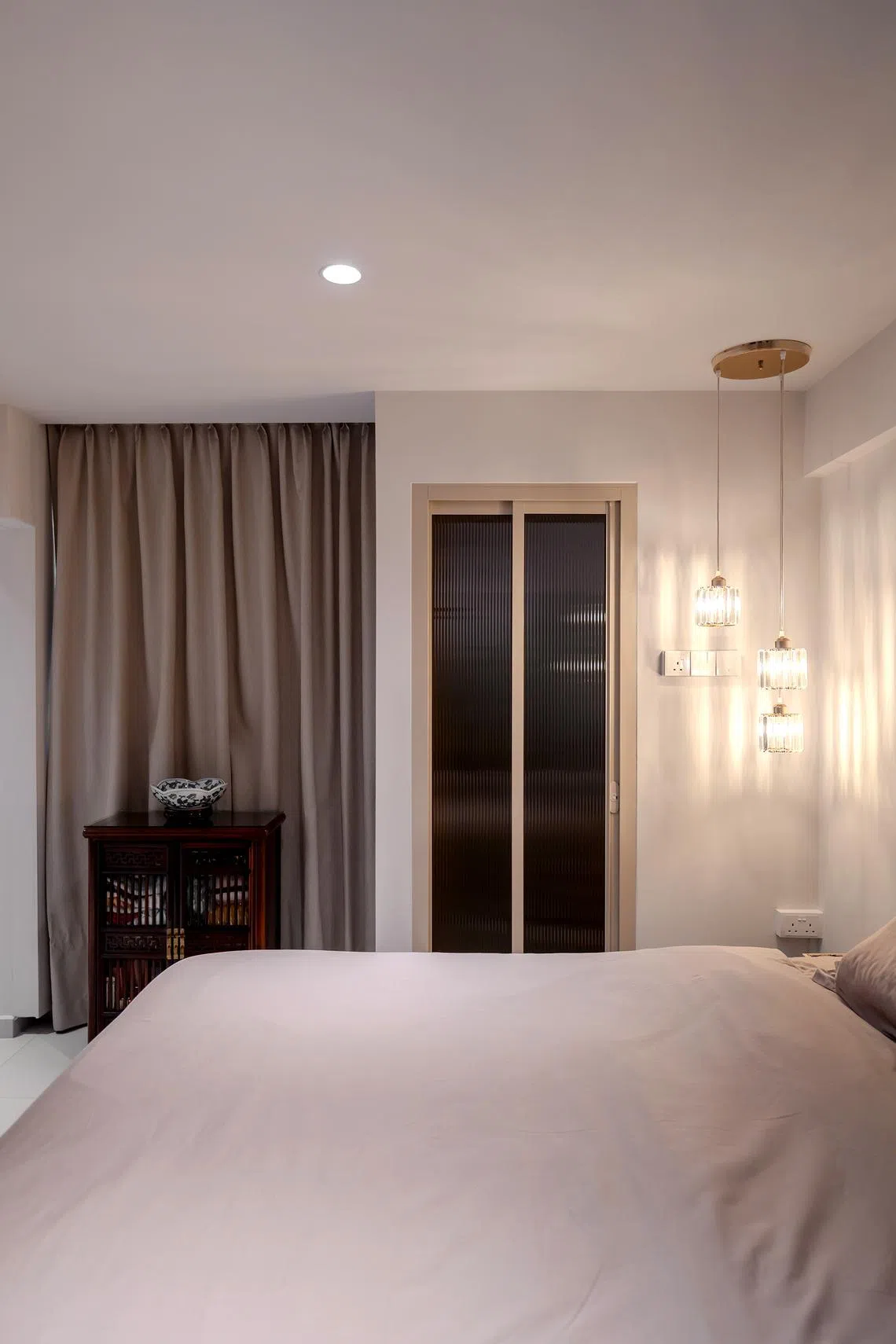 Delicate glass pendant lights hang next to the king-size storage bed.