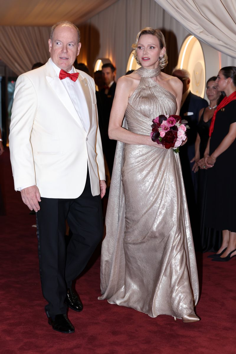 Princess Charlene shines at Monaco’s Red Cross Ball in a dramatic gold column gown, pairing Bond girl glamour with diamonds and Old Hollywood waves.