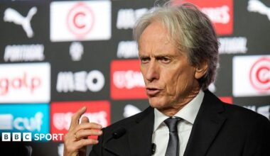 Jorge Jesus, wearing a black suit, gesticulates with his right hand while speaking at a press conference