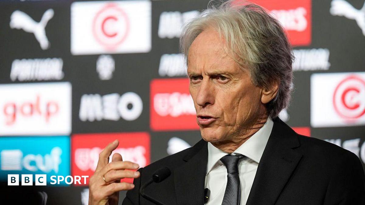 Jorge Jesus, wearing a black suit, gesticulates with his right hand while speaking at a press conference