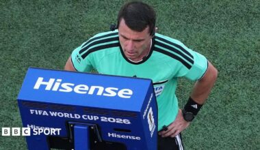 A referee looks into a blue VAR monitor